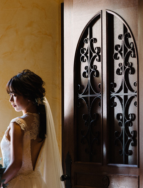 チャペルのドアの隣りにナチュラルな結婚式のドレスを着ている女性が立っています
